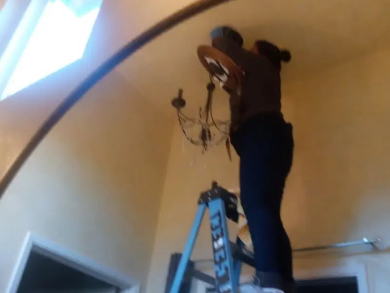 Electrician installing a chandelier in a Manlius residence